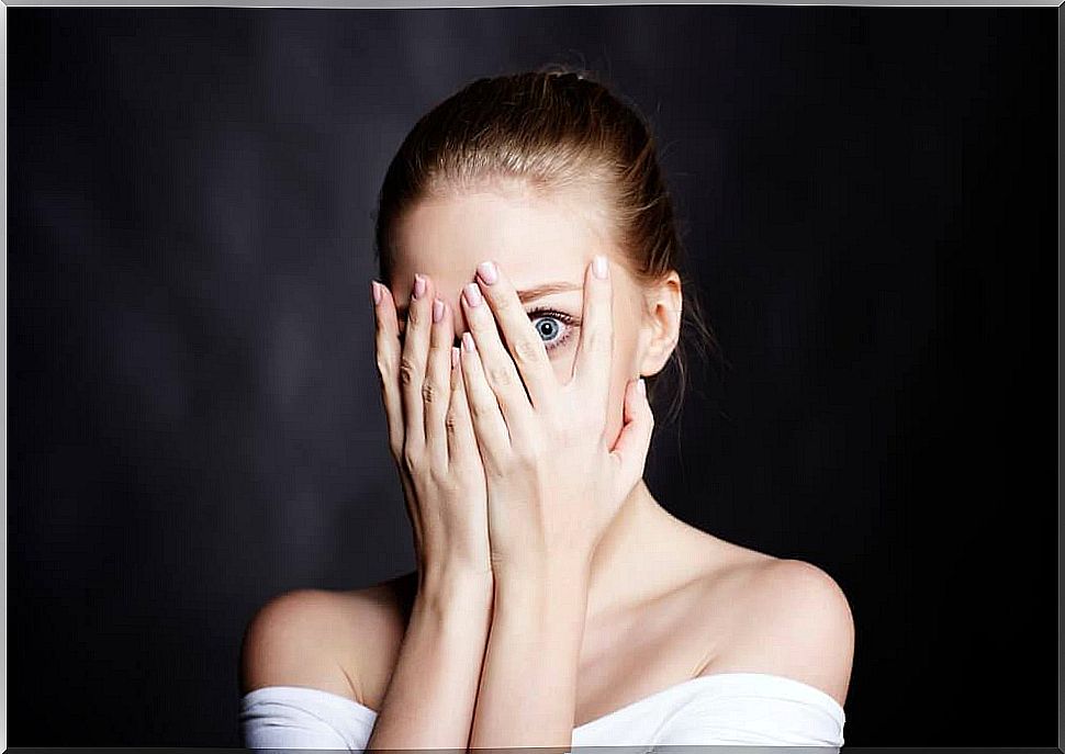 A woman covers her face with her hands.