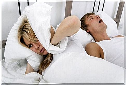 Woman covers her ears because man snores