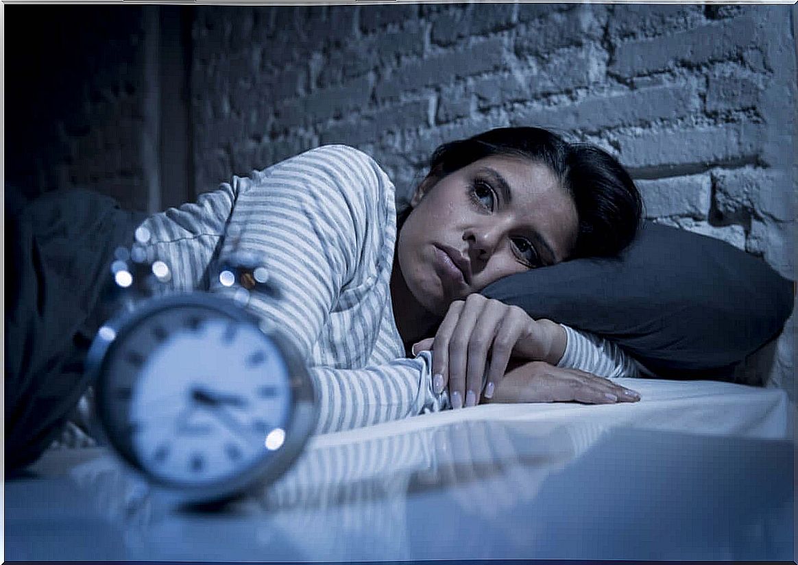 Woman in bed looks at watch sleepless