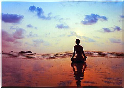 Woman meditates by the sea in the sunset and wants to relieve fear and nervousness