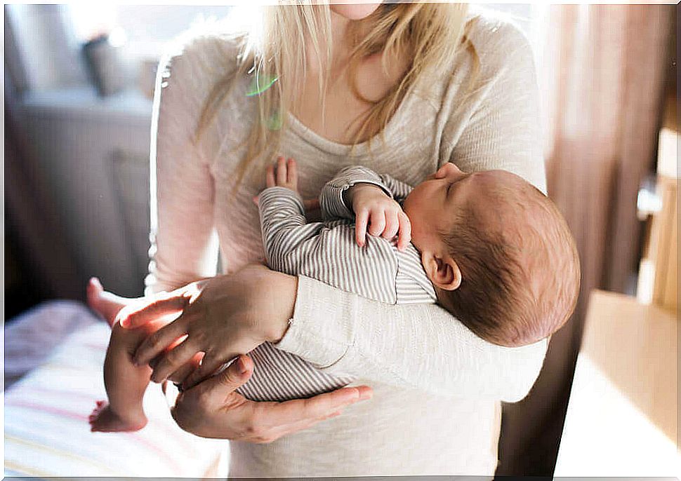 Mother holds baby in her arms - body contact